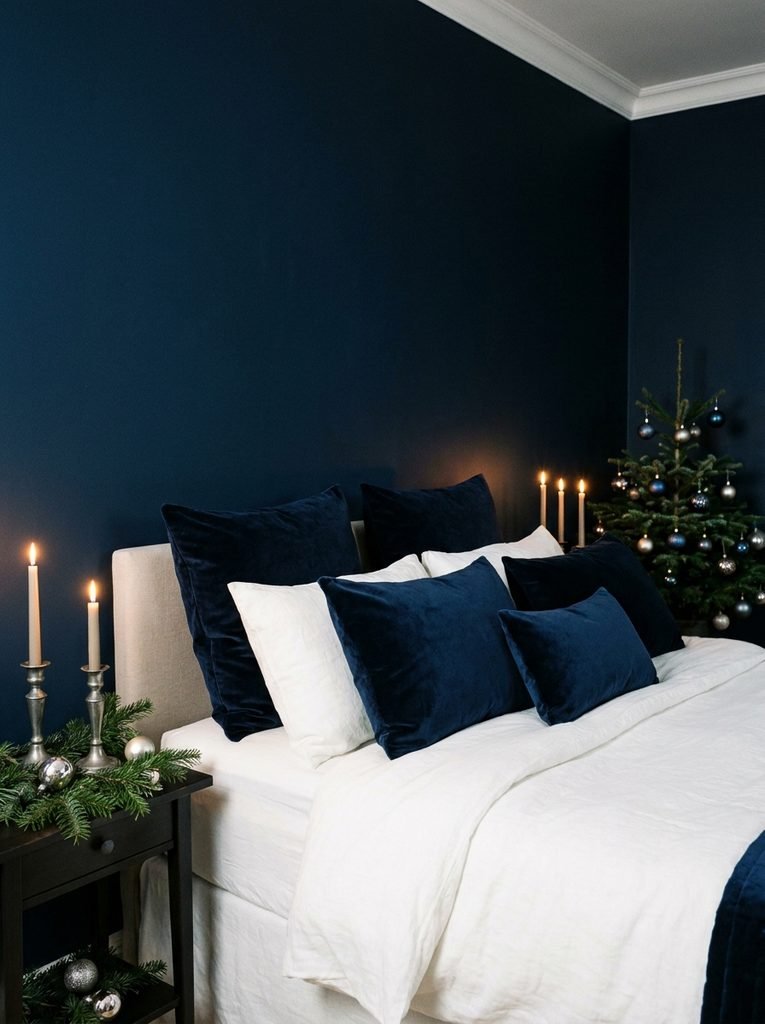 Midnight blue bedroom with white bedding, navy velvet pillows and pewter candle holders for Christmas